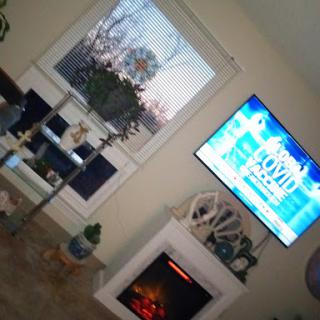 A cozy living room with a television displaying news and a warm fireplace.