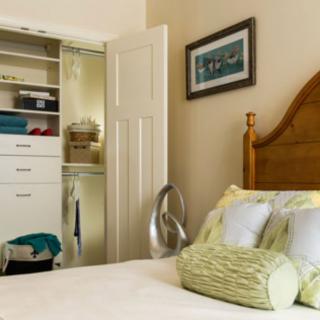 A cozy bedroom interior featuring a neatly organized closet and a well-decorated bed.