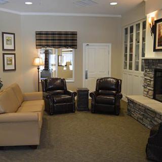 A cozy living room with a sofa, two armchairs, and a fireplace.