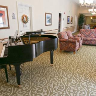 A lobby with a grand piano, patterned carpet, and comfortable seating arrangements.