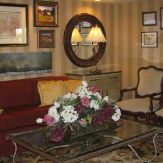 A cozy living room adorned with elegant furniture, a floral arrangement on the coffee table, and artwork decorating the walls.
