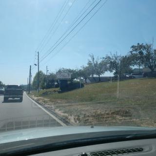 A view of a road with vehicles, trees, and clear blue skies.