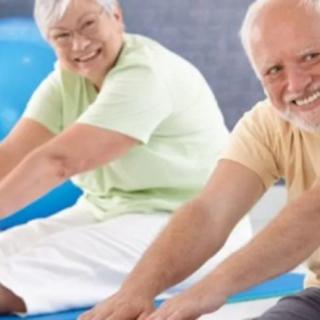 Two seniors smiling while stretching during a yoga session.