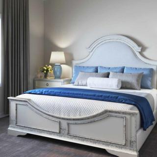 A well-appointed bedroom featuring a stylish bed with a blue and white color scheme, accompanied by coordinated pillows and a bedside lamp.