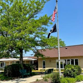 A sunny day at a veterans facility, featuring the American flag and a veterans flag flying proudly.