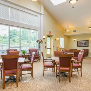A well-lit dining area featuring multiple tables and chairs, with large windows allowing natural light to fill the room.