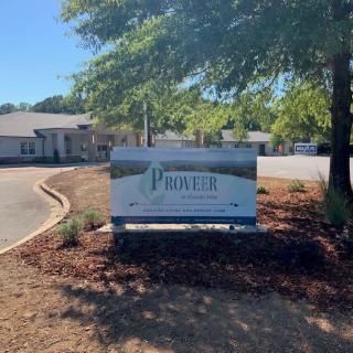 An outdoor sign in front of a professional office building surrounded by trees.