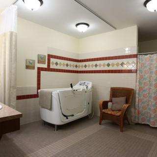 A vintage-style bathroom with a walk-in bathtub and wicker chair.