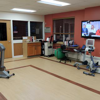 A hospital room with exercise equipment and a TV.