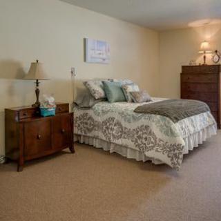 A cozy bedroom with a neatly made bed, a wooden dresser, and bedside lamps.