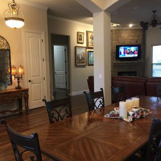 A cozy dining room with a wooden table, chairs, and ambient lighting.