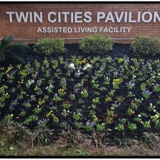 Sign for Twin Cities Pavilion Assisted Living Facility with a garden in front.
