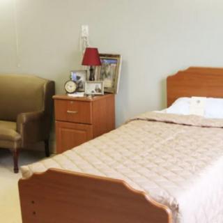 A cozy bedroom with a single bed, nightstand, and chair.