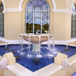 Elegant outdoor fountain with cascading water in front of a large windowed building.