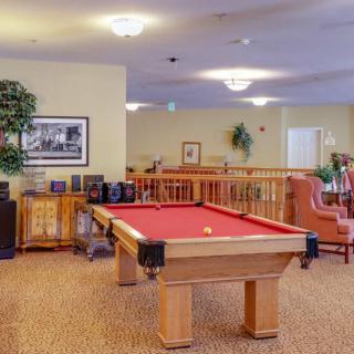 A cozy recreation room featuring a pool table, seating area, and warm lighting.