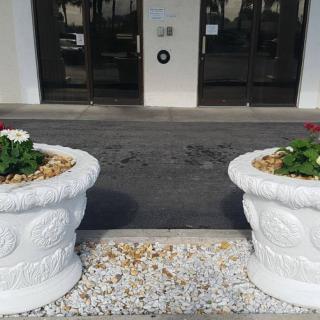 Two large decorative planters with flowers at an entrance.