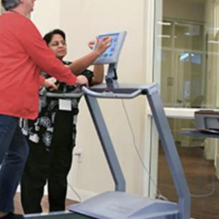 A person receives guidance on using a treadmill in a fitness setting.