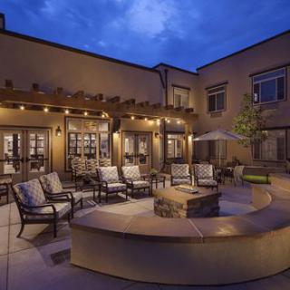 A beautifully lit patio at dusk with comfortable seating and a central fire pit.
