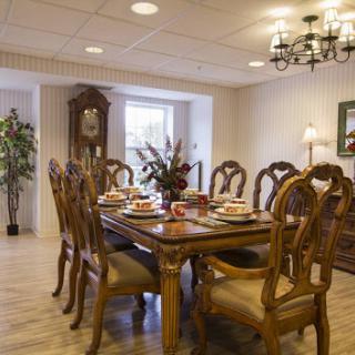 A beautifully arranged dining room featuring an elegant wooden table and chairs, complemented by a chandelier and decorative floral elements.