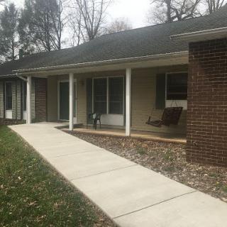 A cozy residential house with a welcoming front porch and well-kept landscaping.
