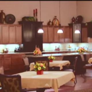 A cozy kitchen interior with tables and chairs, decorated with flowers and warm lighting.