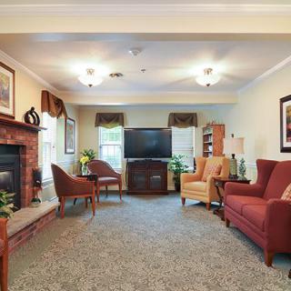 A cozy living room with a television and a fireplace, featuring comfortable seating and warm decor.
