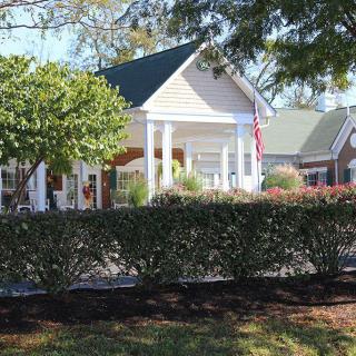 A cozy house with a welcoming front porch surrounded by greenery and trees.