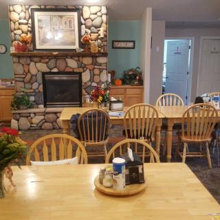 A cozy dining room with wooden furniture and a stone fireplace.