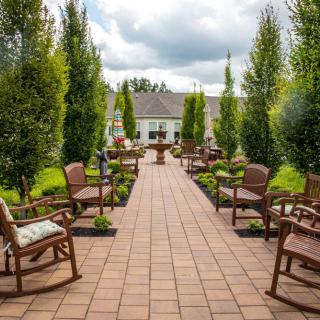 A beautifully landscaped garden path lined with chairs, leading to a quaint building.