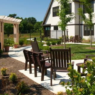 A serene outdoor garden area featuring wooden chairs and a gazebo, perfect for relaxation.