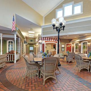 A cozy indoor seating area with wicker furniture and decorative lighting, featuring a brick floor and flags.