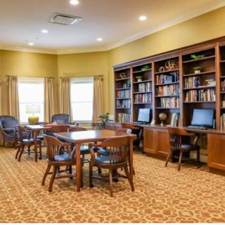 A cozy library with bookshelves, tables, chairs, and computers.