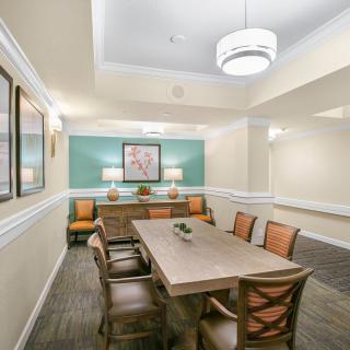 A well-lit dining or meeting room with a wooden table, chairs, and decorative artwork.