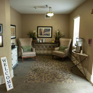 A cozy waiting area with two chairs, artwork, and decorative plants.