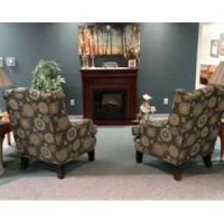 A cozy living room setup with two patterned chairs facing a fireplace.
