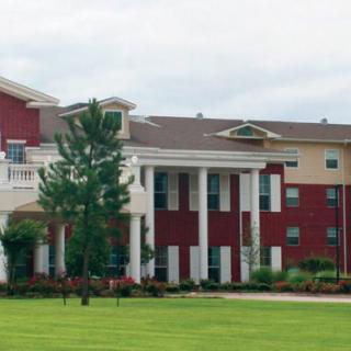 A red and white building with columns set amid a grassy landscape.
