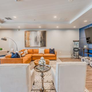 A modern living room with an orange sectional sofa, featuring stylish decor and contemporary artwork.