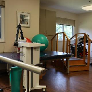 A well-equipped physical therapy room featuring exercise equipment, stairs for rehabilitation, and a green exercise ball.