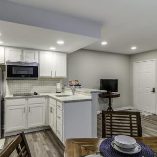 A modern open-concept kitchen with white cabinets and a small dining area.