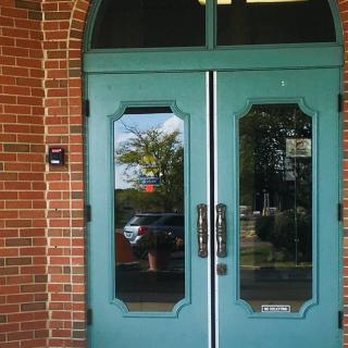 A green double door with glass panels set in a brick building.