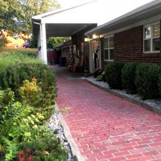 A house with a brick pathway leading through a garden and shrubbery.
