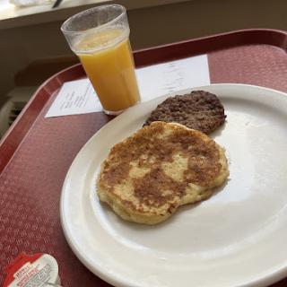 A simple breakfast featuring pancakes, sausage, and orange juice.