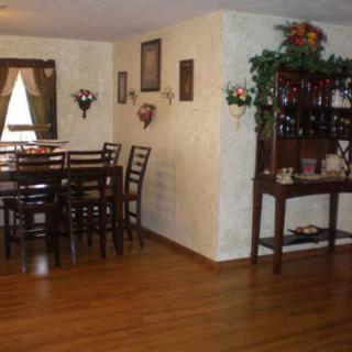 A dining room with a wooden table and chairs, decorated with wall art and greenery.