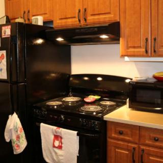 A cozy kitchen with wooden cabinets, a black refrigerator, and a stove with pots on it.