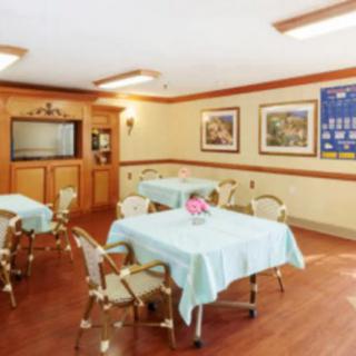 A cozy dining area with neatly arranged tables and chairs, adorned with decorative paintings and a floral centerpiece.
