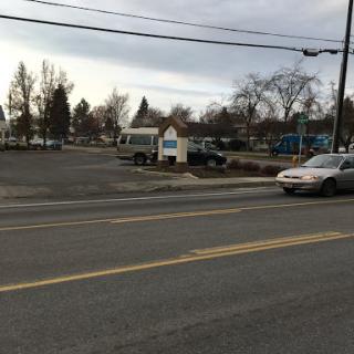 A view of a parking lot with several vehicles under a cloudy sky.