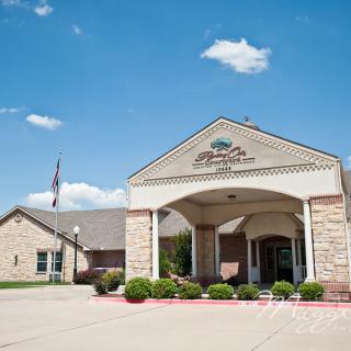 A large brick building with an arched entrance under a partly cloudy blue sky.