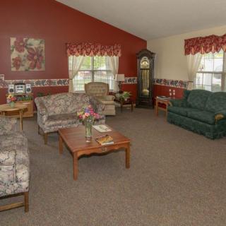A cozy living room with comfortable sofas, a wooden coffee table, and a grandfather clock against red walls.