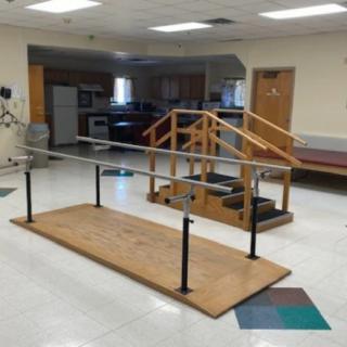 A physical therapy room equipped with parallel bars and stairs for rehabilitation exercises.