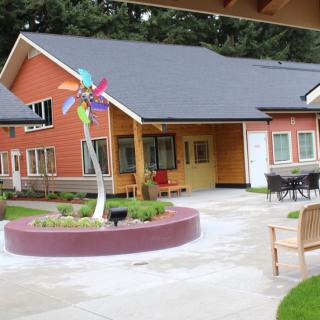 A modern building with a well-maintained courtyard featuring a colorful wind sculpture.